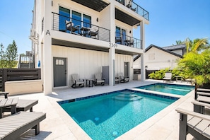 A modern two-story building with a pool, outdoor seating, and a clear sky. - Gulfside Sunset - 2309B   “Anna Maria Island” (Bradenton Beach)