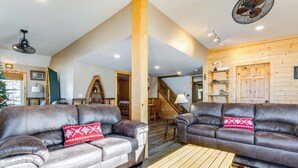 A spacious living room with two leather sofas, a wooden coffee table, and a staircase leading to an upper level. - Lakefront Cabin w/ Shared Beach in Cecil! (Cecil)