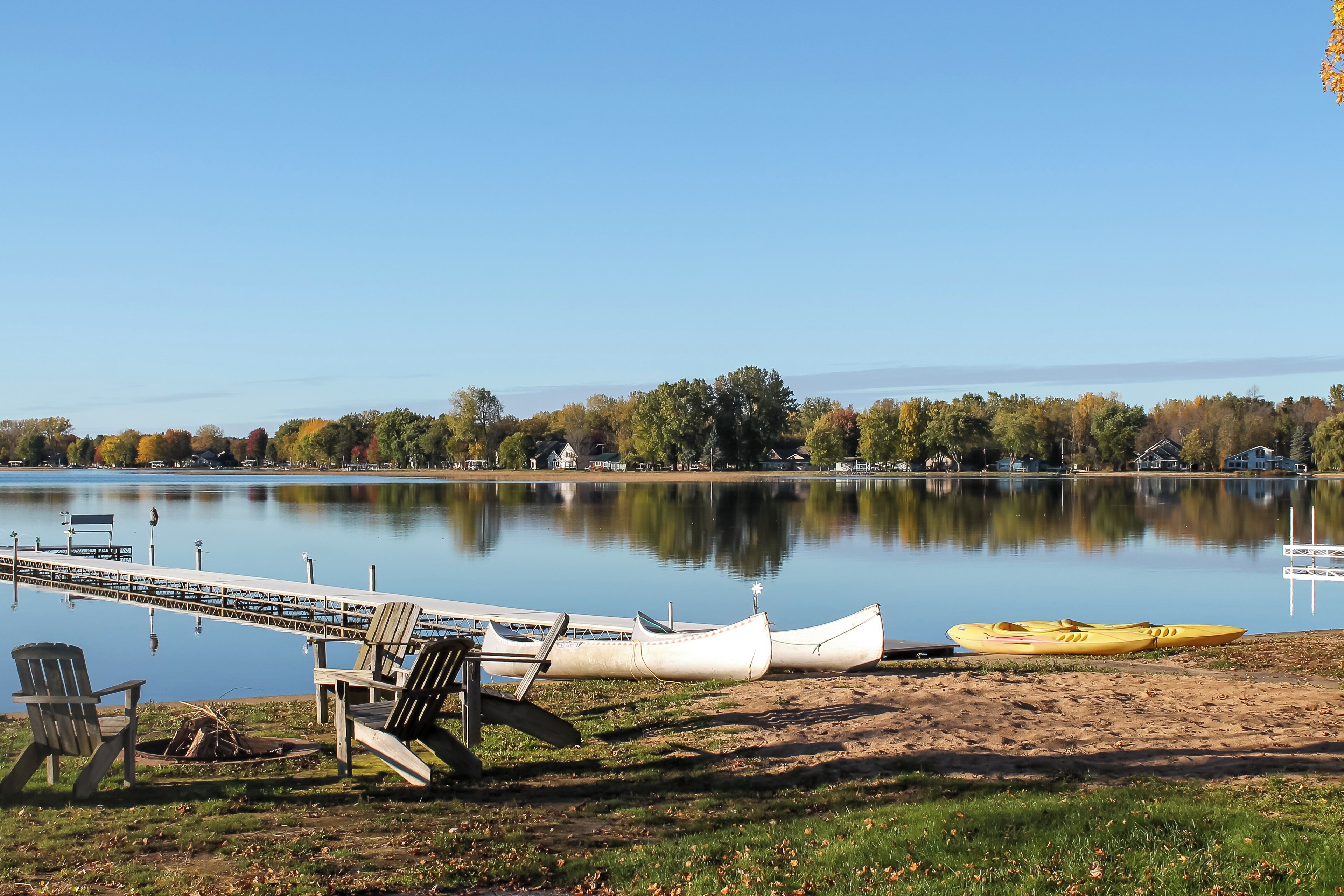 A lakeside view with a dock, boats, and a chair.