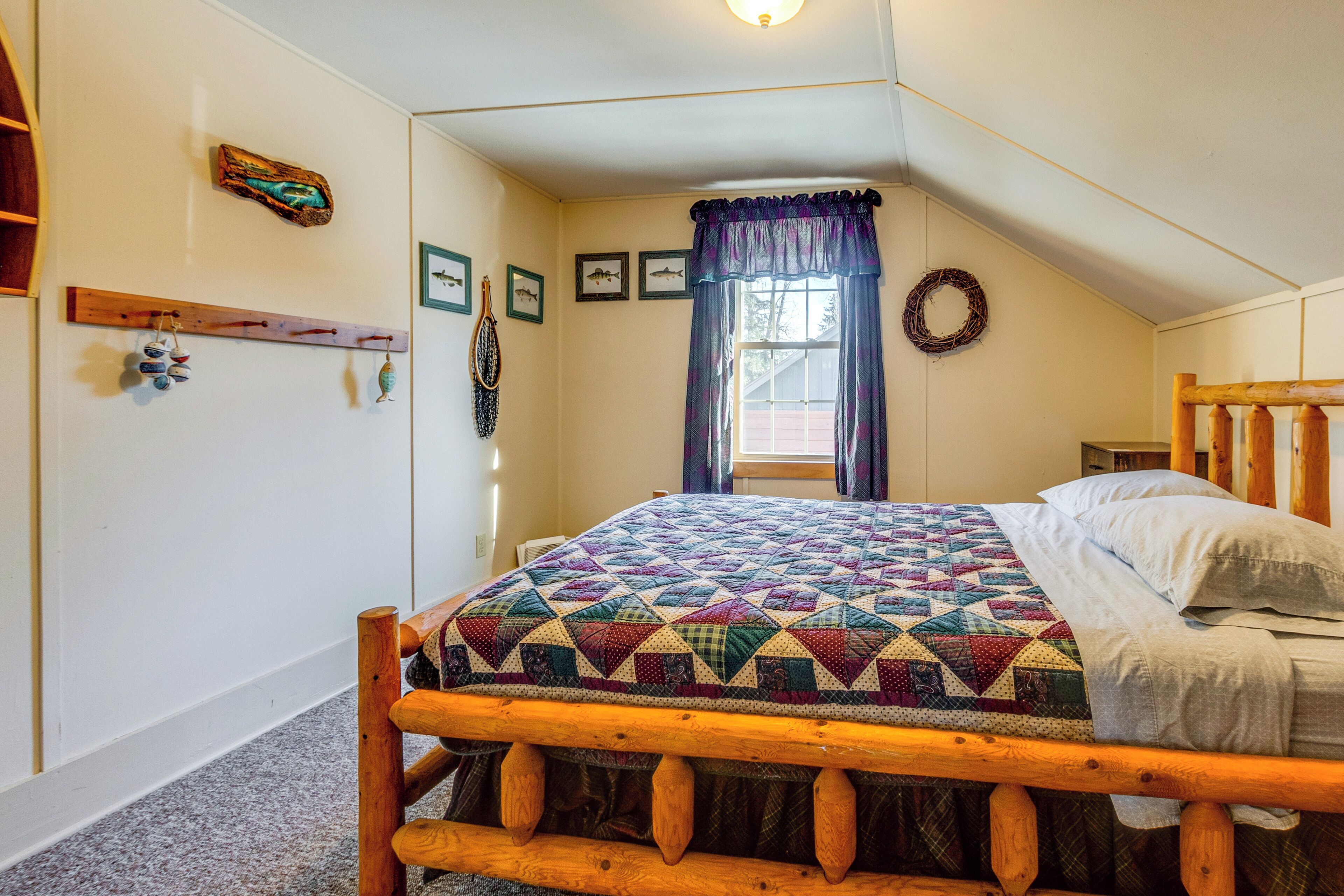 Une chambre à coucher avec un lit en bois, une courtepointe, une fenêtre avec des rideaux et des décorations murales.