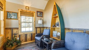 A cozy room with wicker furniture, a wooden bench, and a decorative shelf. - Lakefront Cabin w/ Shared Beach in Cecil! (Cecil)