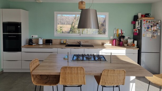 Una cocina moderna con una isla central, estufa a gas y ventana con vistas a un paisaje natural.