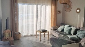 Una sala de estar con sofá, sillón, una mesita y lámpara colgante.
