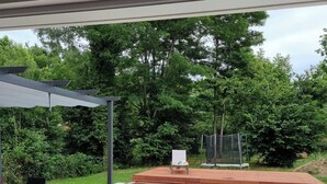 Un patio trasero con piscina, un área de patio techada y una zona de juegos cercada.