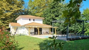 Una casa de dos pisos con techo de tejas, piscina y patio cubierto.