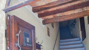 A wooden door with a sign, a staircase with blue steps, and a metal handrail. - PienzaLettings Suites (Pienza)