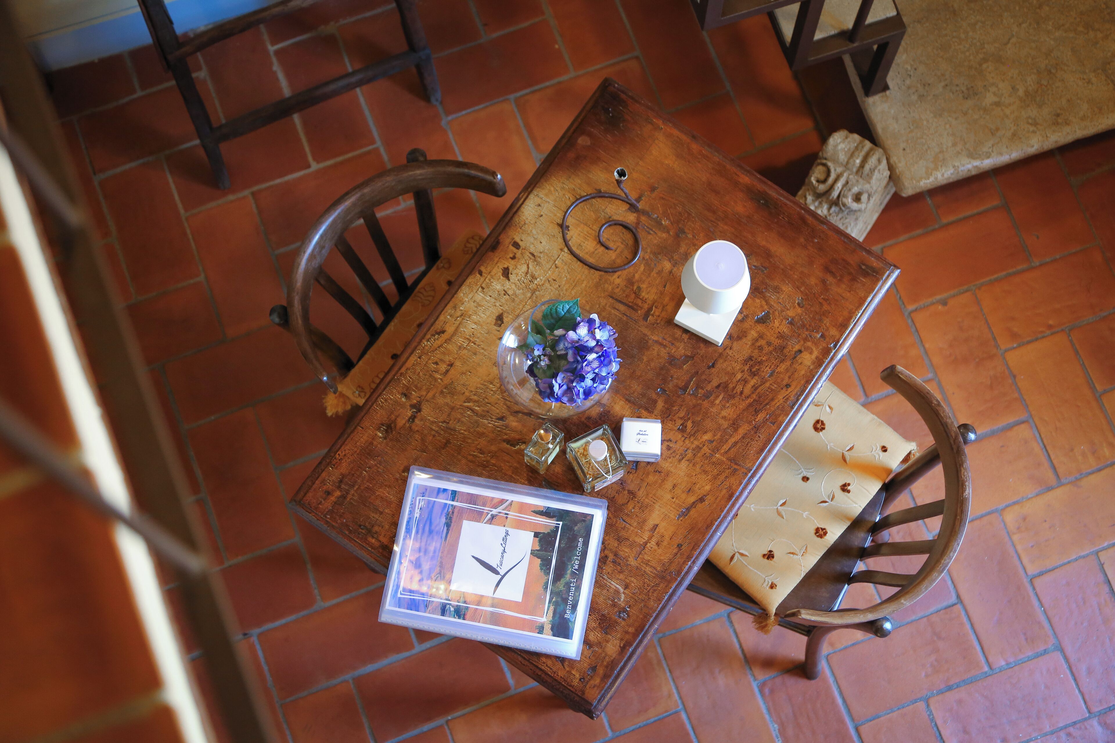 Un tavolo di legno con un quadro incorniciato, un vaso con fiori, una sveglia e una candela.