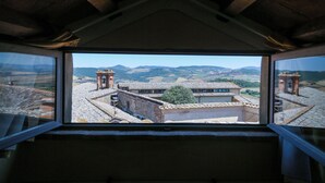 A room with a view of a historic town, featuring stone buildings and a clear sky. - PienzaLettings Suites (Pienza)