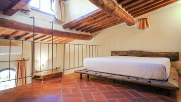 A bedroom with a wooden bed, a sloped ceiling, and a view of the outdoors.