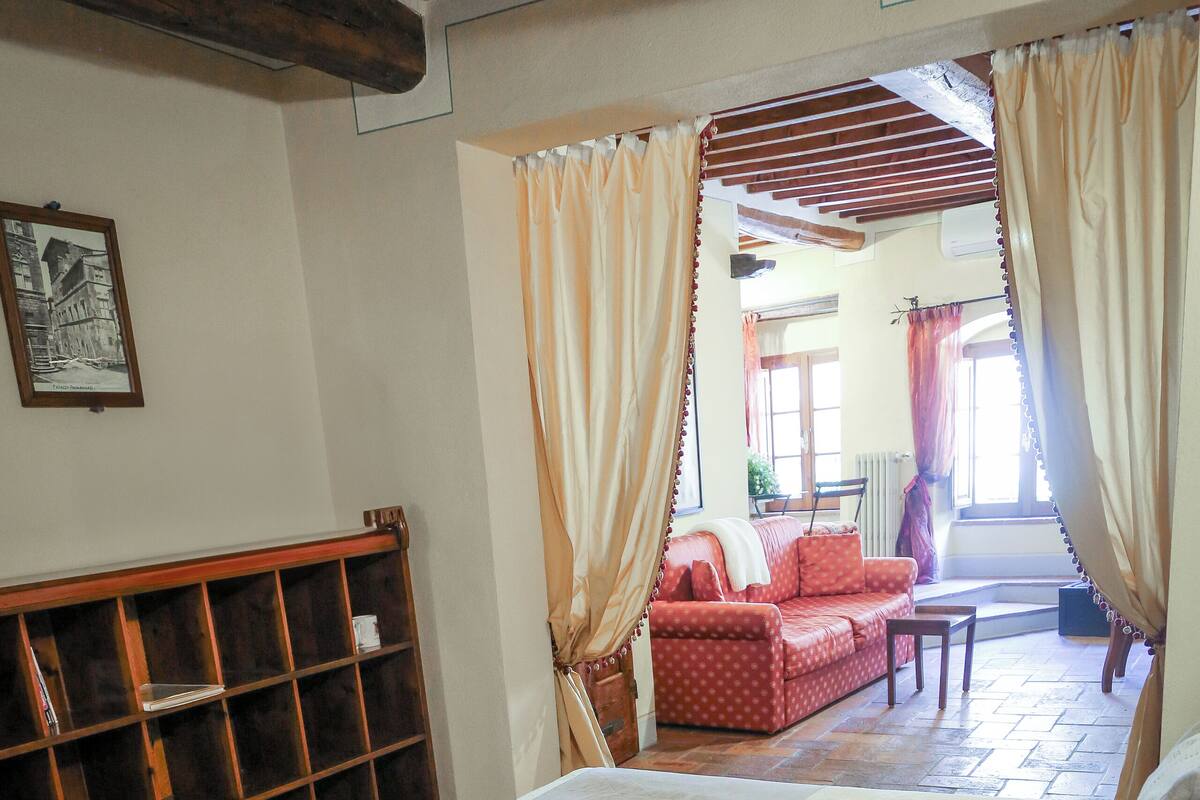 A bedroom with a large bed, a wooden headboard, a red sofa, and a small table.