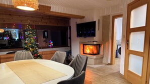 Un salon moderne avec une cheminée, une table à manger et un sapin de Noël.
