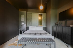 A modern bedroom with a bed, bedside lamp, and a bench.
