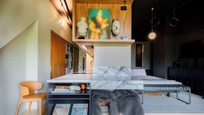 Quarto moderno com cama, cabeceira de madeira, suporte para revistas e uma pequena mesa.