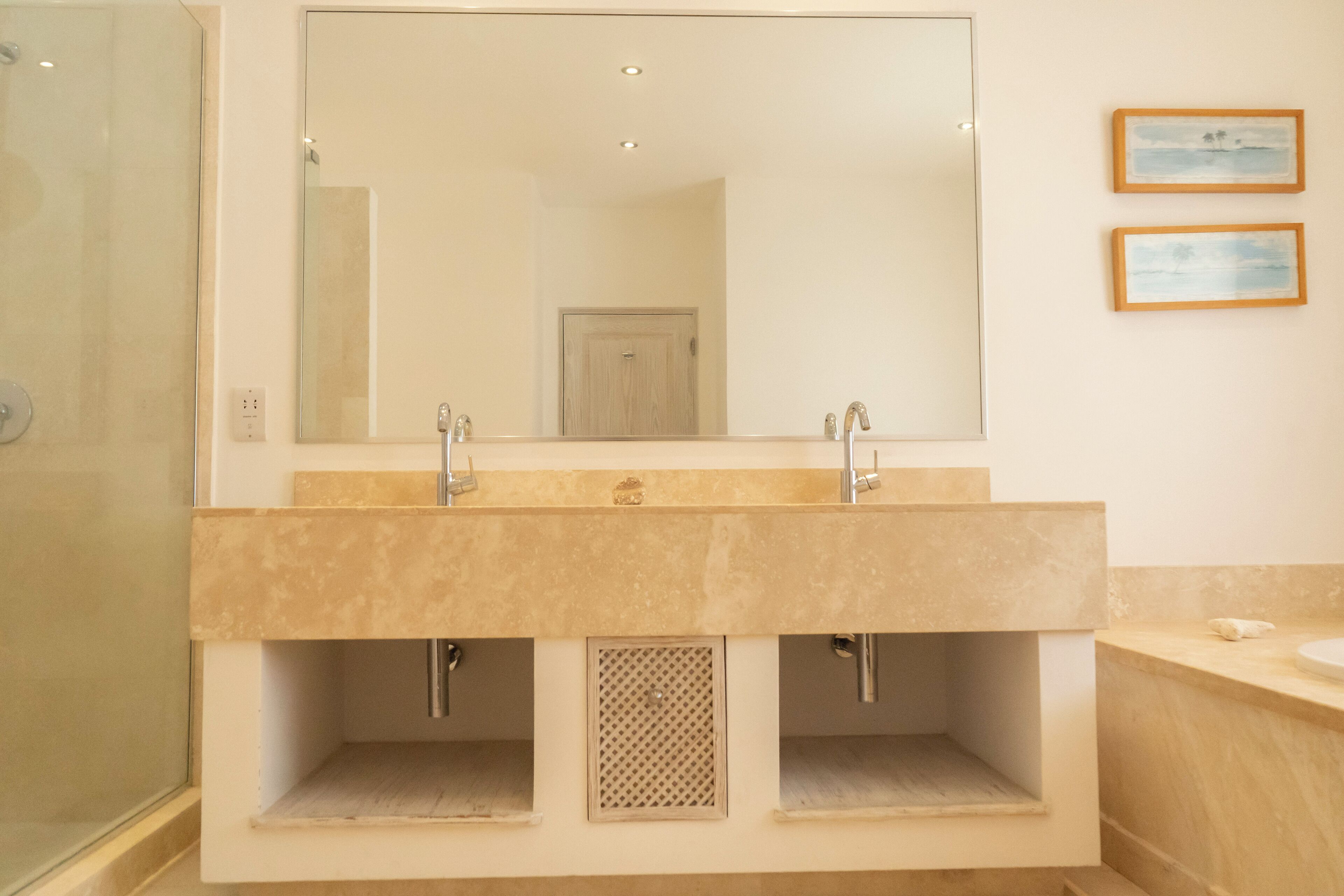 A bathroom with a large mirror, two sinks, and a shower.