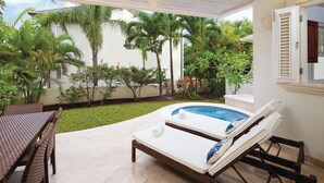 En privat terrasse med et boblebad, liggestole og et spisebord.