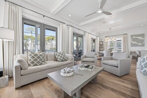 A spacious living room with a large sofa, a coffee table, and a dining area. - Elevated Vacation Living• Fairmont Inspiration by the Bay (Miramar Beach)