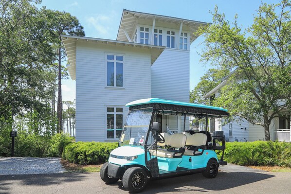 A golf cart parked in front of a house with a covered seating area.