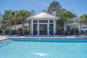 A poolside area with lounge chairs and a small building with large windows.