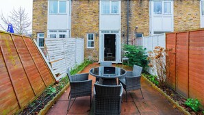 A brick house with a patio, a round table, and four chairs. - Cosy 4BD Flat in Stockwell with Private Patio (Greater London)