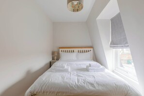 A bedroom with a bed, a nightstand, a lamp, and a window with a view.