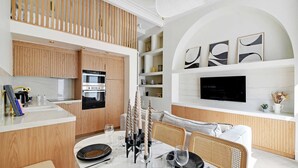 A modern kitchen with wooden cabinets, a built-in oven, and a dining area with a white table set for four.