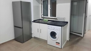 Una cocina compacta con refrigerador, lavadora y microondas.