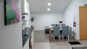 Un comedor con mesa y sillas, una cocina con armarios y encimera, y una puerta con extintor.