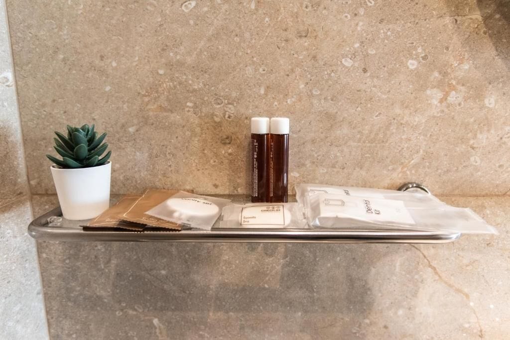 A countertop with a small potted plant, two bottles, and a package of dental floss.