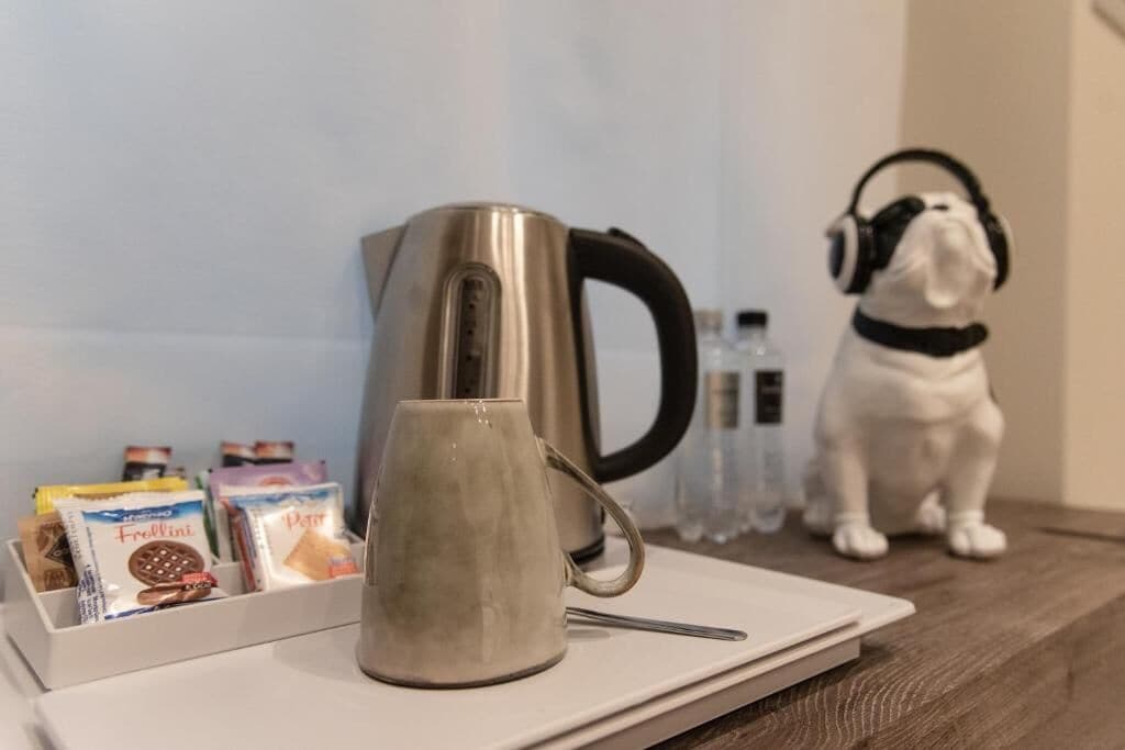 A kitchen area with a kettle, a mug, and a dog wearing headphones.