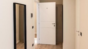 A hallway with a white door, a mirror, and an air conditioning unit. - XXIV Domus Luxury Suites (Rome)