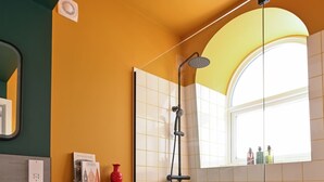 A modern bathroom with a white toilet, a glass-enclosed shower, and a window providing natural light. - Private En-Suite Room | Walk to Angel Station | Near Shoreditch (London)
