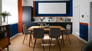 A modern kitchen with a wooden dining table, four chairs, and a vase of flowers. - Lux 4-Bedroom Triplex Close to Angel & Shoreditch (London)