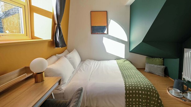 A modern bedroom with a bed, a desk, and a view of the city. - Lux 4-Bedroom Triplex Close to Angel & Shoreditch (London)