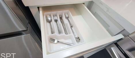 A drawer with utensils including a fork, knife, spoon, and spoon rest.