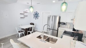 A modern kitchen with a central island, stainless steel appliances, and pendant lighting. - Villas De Laguna 2 3 Bedroom Townhouse (South Padre Island)