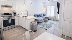 A modern kitchen with white cabinets, stainless steel appliances, a central island with a sink, and pendant lighting. - Villas De Laguna 2 3 Bedroom Townhouse (South Padre Island)