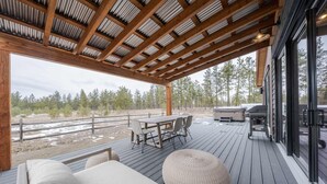 A covered outdoor deck with a wooden table and chairs, a sofa, and a grill area. - Wilderness Club Hideaway (Eureka)