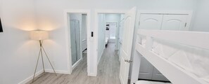 A hallway with a floor lamp, white doors, and a view into a bedroom. - Villas De Laguna 3 3 Bedroom Townhouse (South Padre Island)