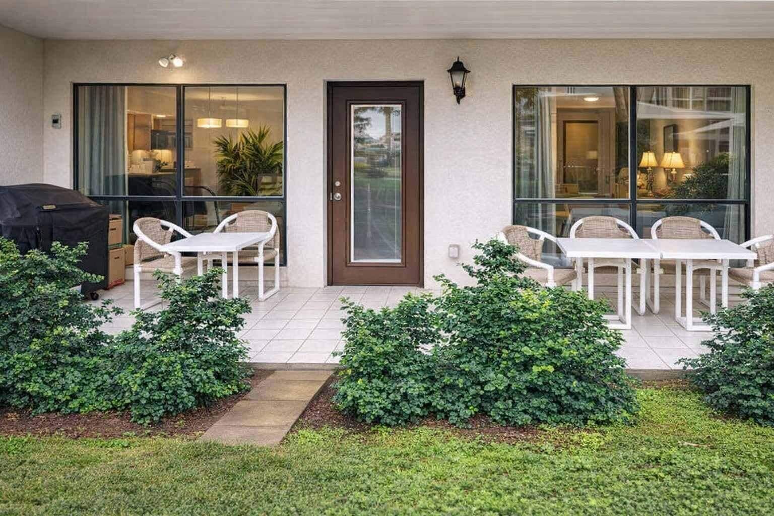 Un patio cubierto con una parrilla, asientos exteriores y una puerta que da al interior.