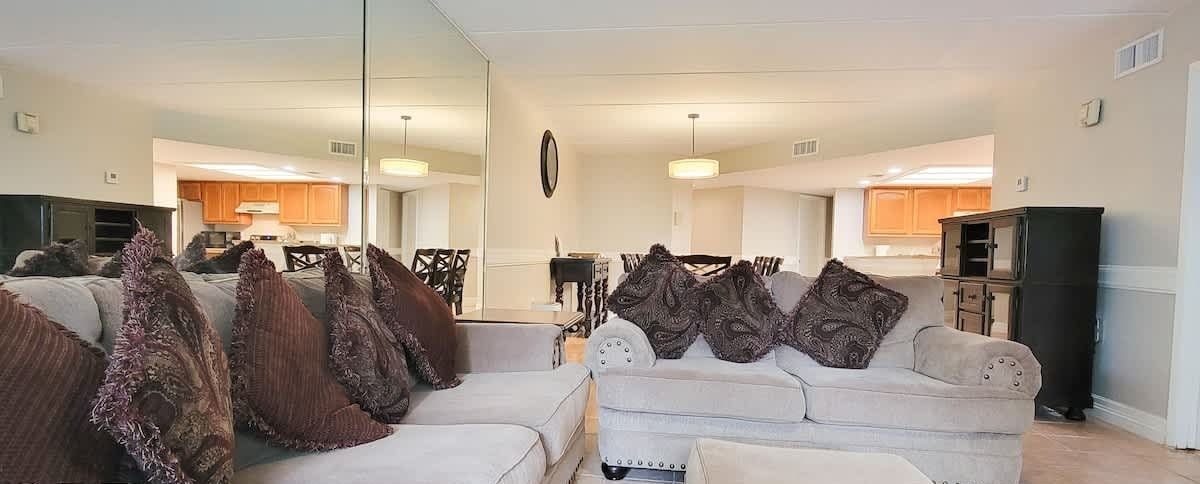 Een ruime woonkamer met een grote zithoek, een salontafel en een eethoek op de achtergrond.