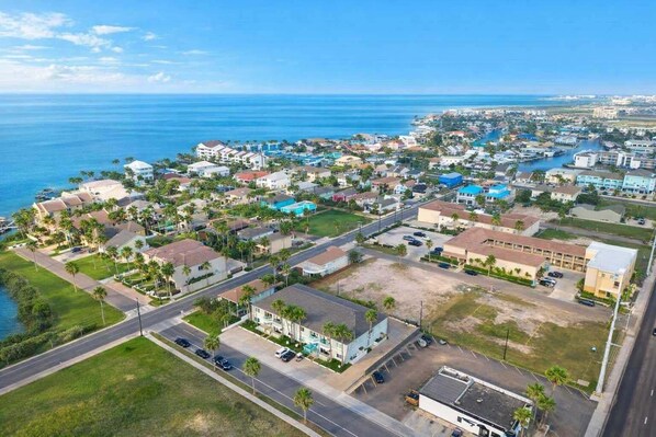 Vue aérienne d’un quartier résidentiel situé sur la côte, avec des maisons, des routes et un port de plaisance.