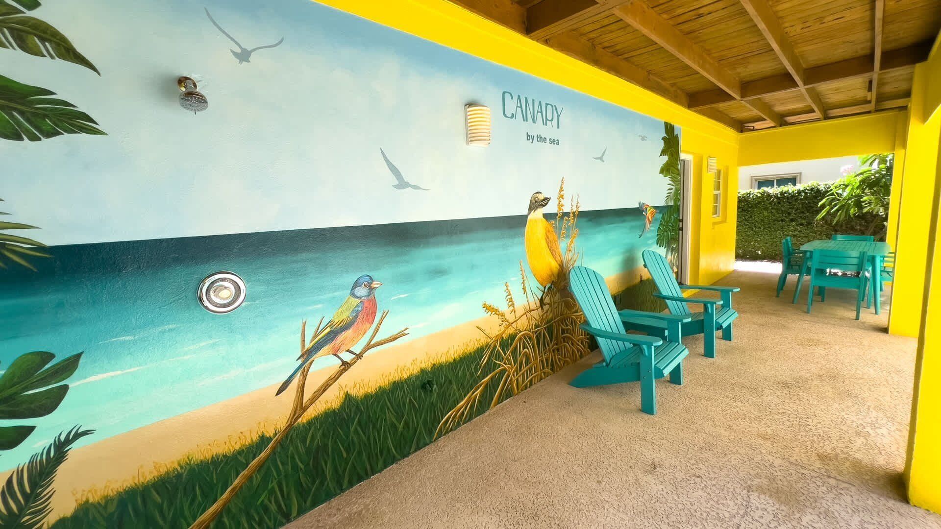 A beach-themed mural with birds and the text "CANARY by the sea" on a yellow wall.