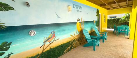 A beach-themed mural with birds and the text "CANARY by the sea" on a yellow wall.