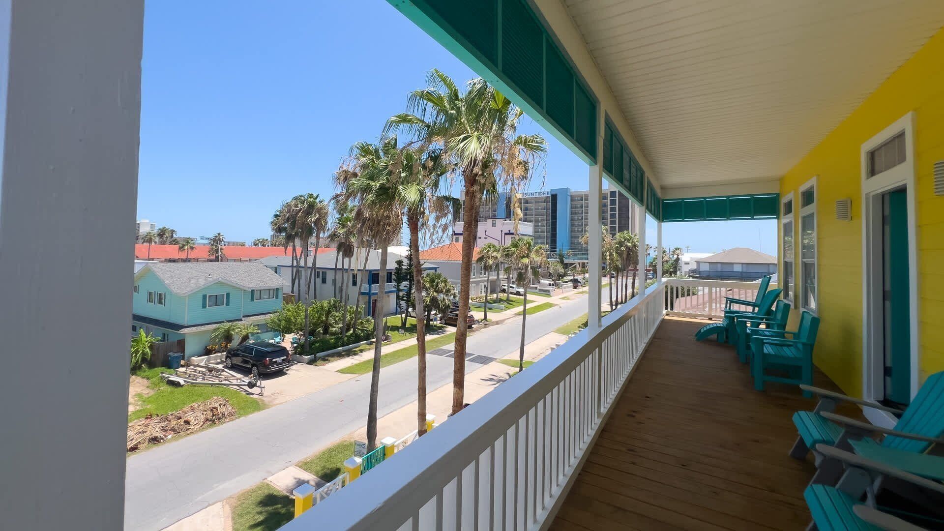 A balcony with a view of a street lined with palm trees and buildings.