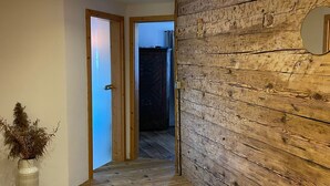 A hallway with wooden flooring, a wooden accent wall, a mirror, and a plant. - Beautiful, renovated 100 sqm vacation apartment in a former farmhouse in the Allgäu (Maierhöfen)