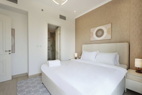 Een hotelkamer met een groot bed, nachtkastjes, een deur en een douche.