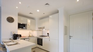 A modern kitchen with white cabinetry, a microwave, a stove, and a sink.