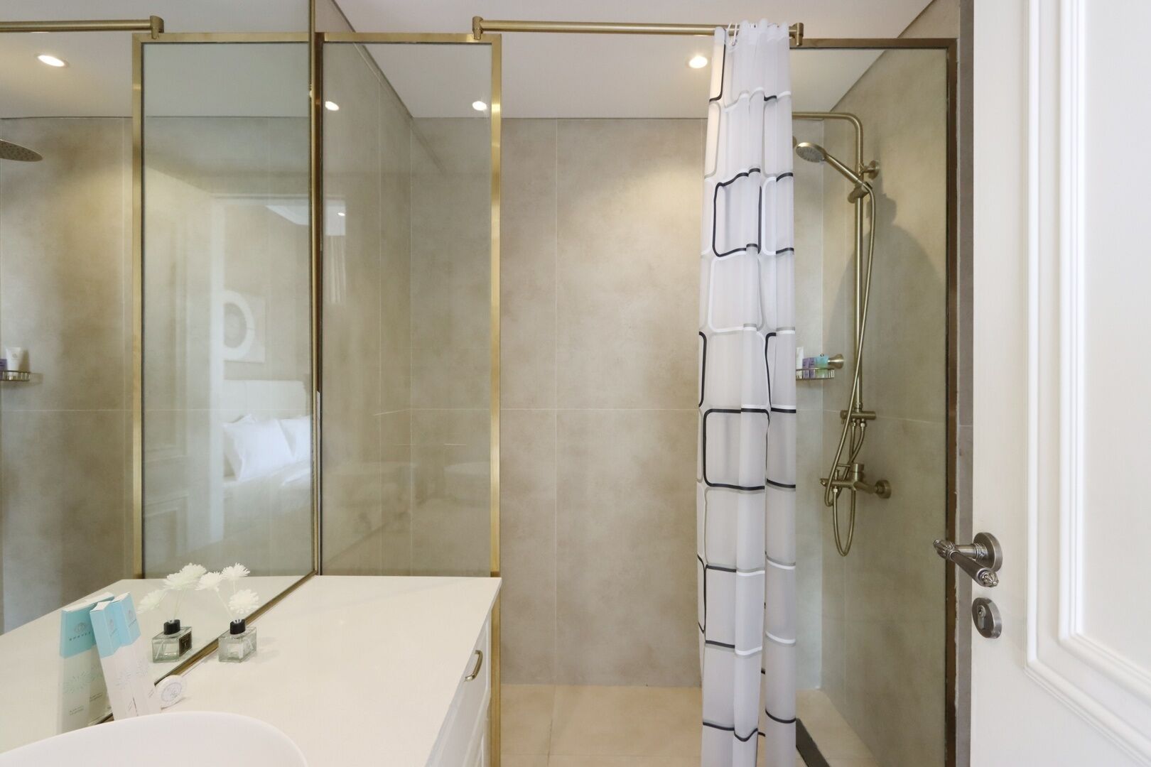 Een moderne badkamer met een glazen douchecabine, een witte badkuip en een wastafel met toiletartikelen.