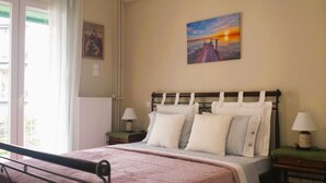 Een slaapkamer met een bed, twee nachtkastjes, een raam met zonwering en een schilderij aan de muur.