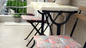 Een balkon met twee stoelen, een tafel en een plant in een pot.